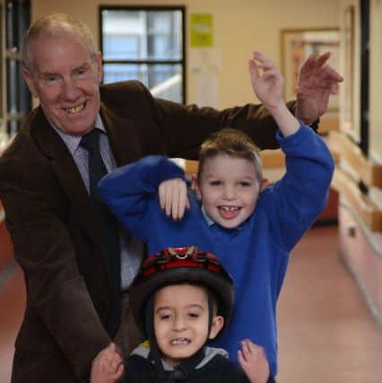 Ray Matthews presents a modified trike to Newman School pupils Josh Harrod and Junayd Boston