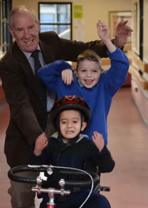 Ray Matthews presents a modified trike to Newman School pupils Josh Harrod and Junayd Boston