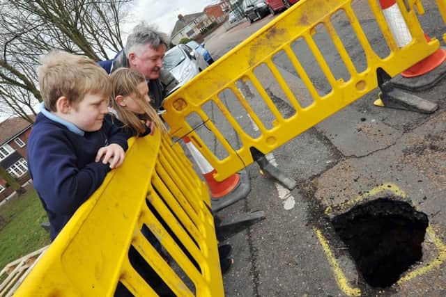 A hole has appeared in the road opposite Sir Edmund Hilary School in Worksop, further investigation revealed it to be an old well. Pictured inspecting the hole are Coun Glynn Gilfoyle with Sir Edmund Hilary pupils Lewis Smith, 10 and Alys Hoyle, 10 (w130321-4b)