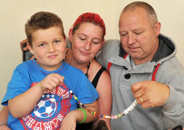 The family of nine-year-old Bailey Hancock who has leukaemia are fundraising to raise money towards a special holiday.  Pictured are Bailey Hancock, nine with Dad Steve and Mum Lisa looking at his Beads of Courage, given to him by Sheffield Children's Hospital (w121009-11b)