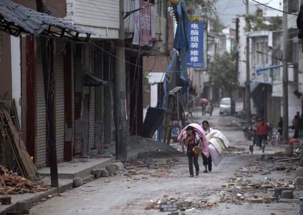 In this photo released by China's Xinhua news agency, people carrying their belongings walk in quake-damaged Gucheng Village, Longmen Township, Lushan County, southwest China's Sichuan Province, Saturday, April 20, 2013. A powerful earthquake struck the steep hills of Sichuan province Saturday, nearly five years after a devastating quake wreaked widespread damage across the region. (AP Photo/Xinhua, Fei Maohua) NO SALES