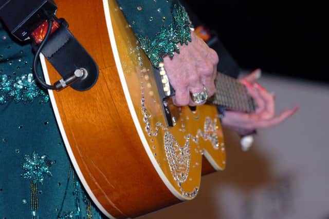 Dolly Parton plays along with her damaged guitar