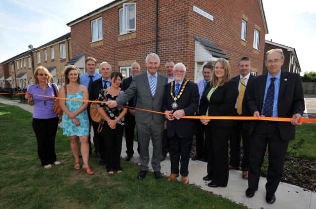 Official opening of new houses at Brocklesby Mews, pictured cutting the ribbon is Coun Malcolm Parish with Acis vice chair John Cawdell, watched by Acis chief executive Valerie Waby and MD of Gelder Group Steve Gelder MBE and representatives from West Lindsey District Council, Gelder Group and Acis (w130904-2a)