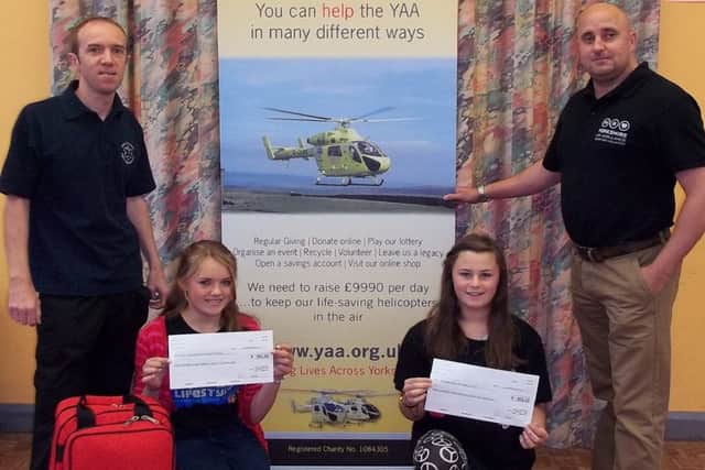 Jade Anderton and Abygayle Wood prerent cheques to the Five Villages First responders and Yorkshire Air Ambulance