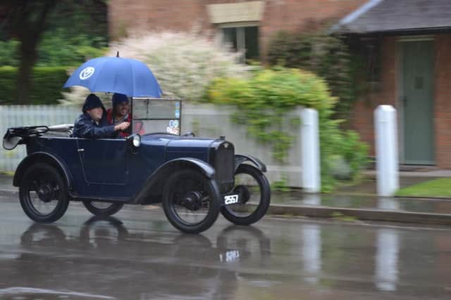 A driver and passenger find a novel way to keep the rain out of their Austin Seven during the event