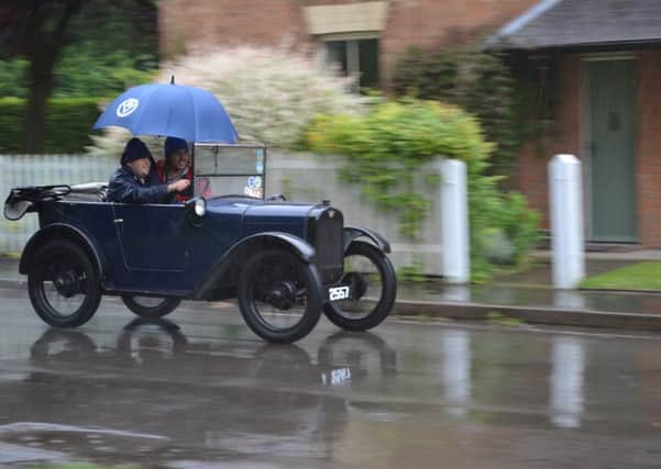 A driver and passenger find a novel way to keep the rain out of their Austin Seven during the event