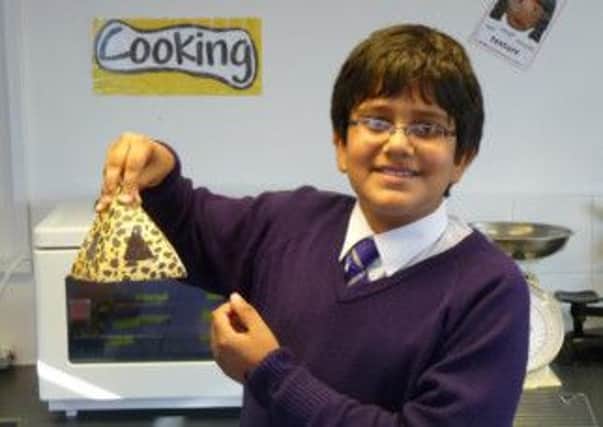 Year Six pupil Eshaan Chandran proudly holding his homemade muffin in the box that he designed and made to house it at the Rudston School maths week