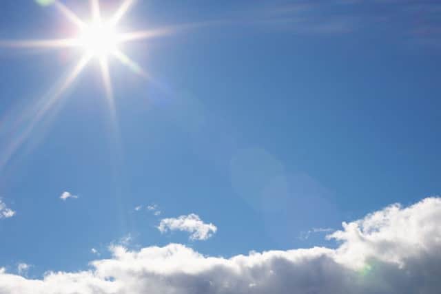 Bright sun with rays shining above clouds
