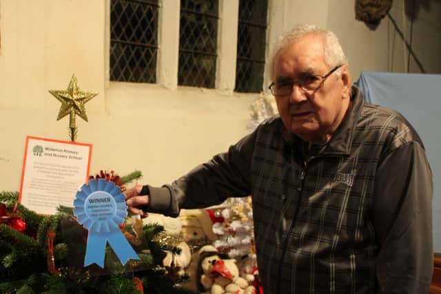 Sid Burgess pins the winners rosette to the winning tree in the Misterton Christmas Tree Festival