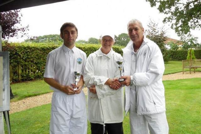 WET WINNERS! -- father and son Mike and Richard Bilton receive the Jubilee Park Invitation Cup from Cass Hewson, of Woodhall Spa Croquet Club.