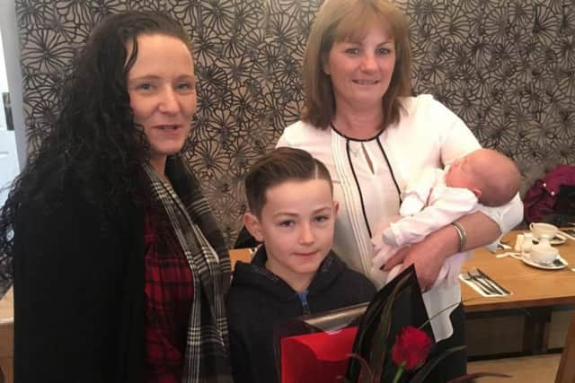 Michelle Handshaw and her son Hayden Smith present Nichola Barclay, who holds baby Gracie, with a rose award.