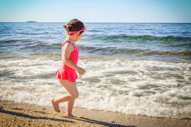 Girl paddling on beach. Photo by Pixabay.