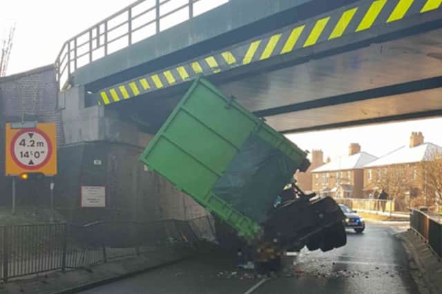 A skip lorry has become wedged under a bridge on Lea Road
