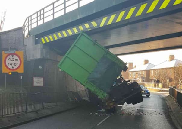 A skip lorry has become wedged under a bridge on Lea Road