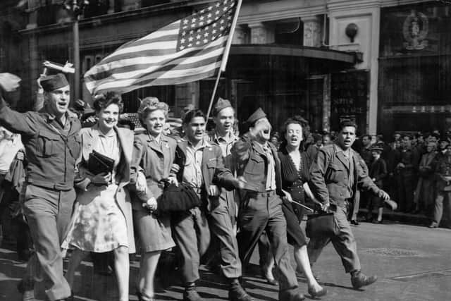 On hearing on radio of the Japanese offer to surrender on 10 August 1945, American soldiers and English girls parade the 'Stars and Stripes' past the famous Criterion restaurant in Piccadilly Circus, London (Photo: IWM)
