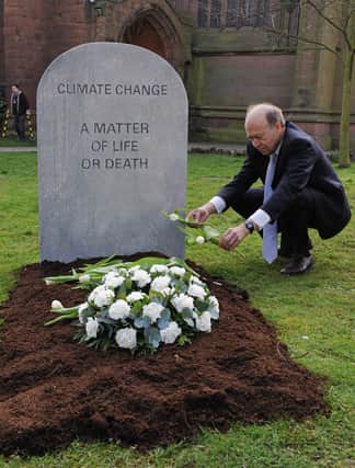 Climatologist Dr James Hansen, and Director of NASA's Goddard Institute for Space Studies, poses for pictures beside a mock grave reading "Climate Change, a Matter Of Life Or Death" (CARL DE SOUZA/AFP via Getty Images)