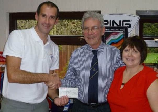 Derek Banister presents Gary Clarke with the cheque, watched by Kellie Hadland.