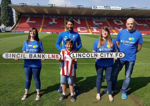 Represenatives from St Barnabas Hospice with a young Lincoln City fan and club manager Danny Cowley (centre). EMN-180126-122157001