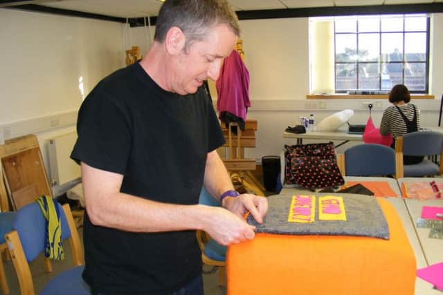 Working on reupholstering a footstool to accompany the sofa in the homelessness workshop. EMN-180127-133258001