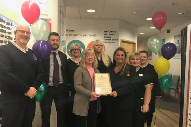 Lynda Clark, Volunteering Co-ordinator for T.E.D (centret left), presents an award for being age friendly to Louise Young, manager of Boots Opticians, watched by staff and Steve Andrews (left), manager of the Hildreds Centre in Skegness. ANL-180102-150536001