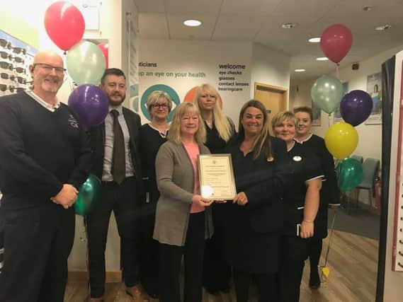 Lynda Clark, Volunteering Co-ordinator  for T.E.D (centret left), presents an award for being age friendly to Louise Young, manager of Boots Opticians, watched by staff and Steve Andrews (left), manager of the Hildreds Centre in Skegness. ANL-180102-150536001