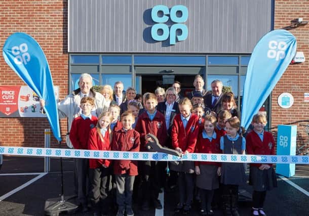 James Latham (aged 10) and Lucy Major (aged 10) cut the ribbon, with their classmates from the Sutton on Sea Primary School, together with local councillors and Jayne Snowden (Store Manager). Photo: Les Gibbon.