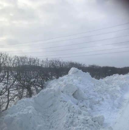 Piled high - the snow drifts pushed aside by James and Simon Burton in their tractor in Leasingham. EMN-180203-114836001
