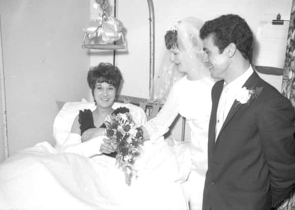 Bridesmaid-to-be Peggy Bray, of Friskney, ended up in London Road Hospital, Boston, rather than church after suffering a broken arm in a car accident in 1968. Here, she receives the bouquet from bride Pamela Wray by way of consulation. EMN-180314-163732001