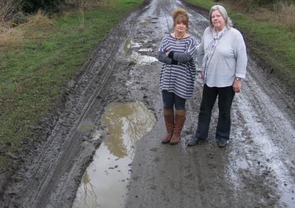 War zone - Samantha Stanley and neighbour Caroline Brice on one of the worst sections of the Helpringham Fen road. EMN-180320-105251001