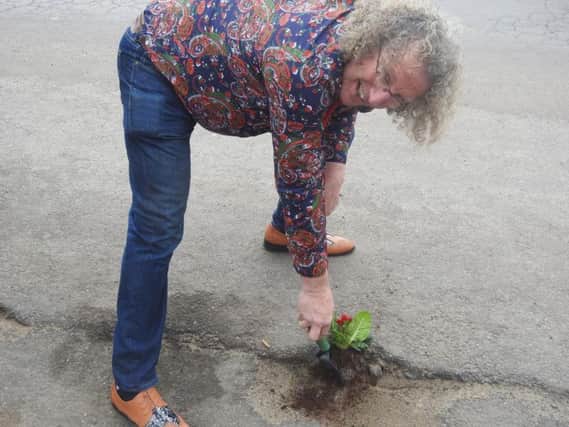 Coun Phil Gaskell planting primroses in potholes down Scarbrogh Avenue, Skegness. Photo: Tony Jackson. ANL-180326-181336001