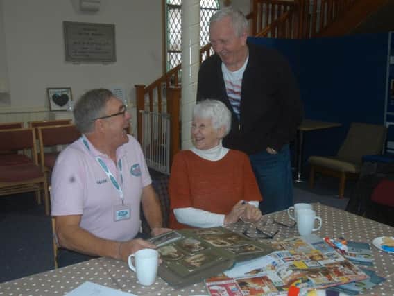 Mark Bamford of Sleaford Museum Trust looking through an album with Ann and Martyn Shearing.