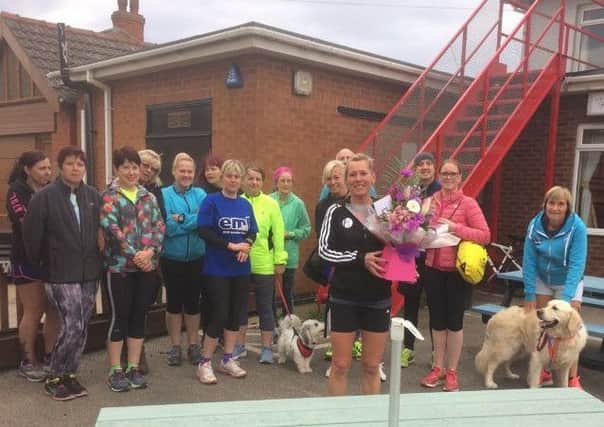 Paula is presented with a bouquet by clubmates after completing her 100th marathon at London EMN-180430-105926002