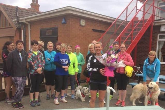 Paula is presented with a bouquet by clubmates after completing her 100th marathon at London EMN-180430-105926002