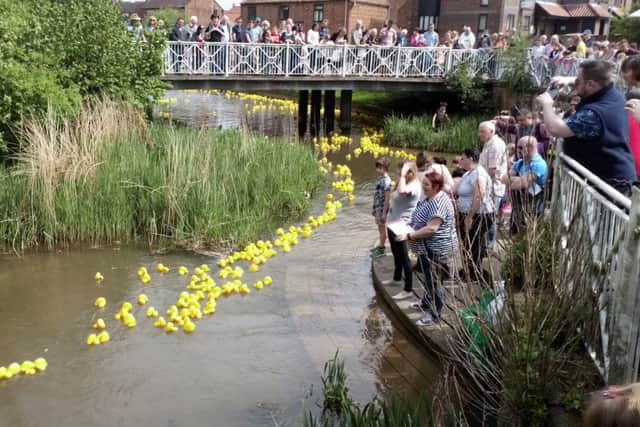 Spectators watch as the rubber replicas are swept along the River Bain with ease. EMN-180514-105908001