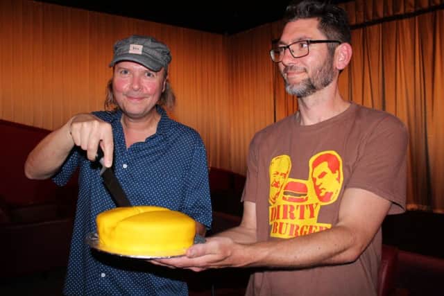 Director Michael Cumming cuts into a slice of 'Cake', alongside event organiser Laurence Schlachter.
