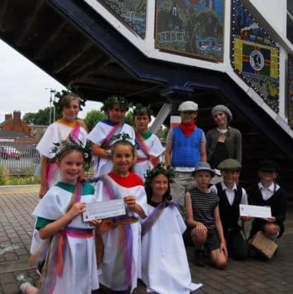 Heckington and Church Lane school pupils in costume beneath their new mosaics on Sleaford station. EMN-180720-120501001