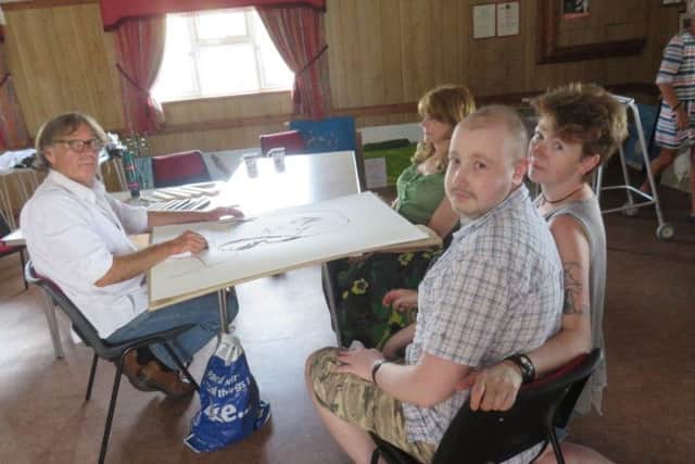Artist Jake Sutton at work, watched by Connor Creasy and his mum Verity.