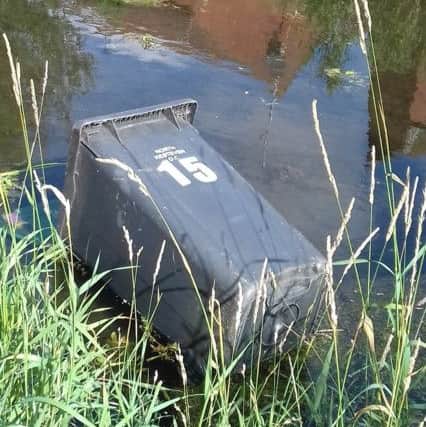A wheelie bin washed up at the side of the river. EMN-180725-122045001