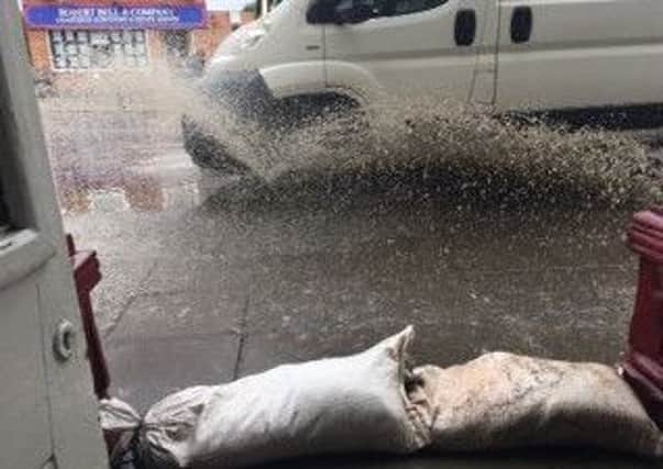 This photo, taken last September, shows a passing van send  water cascading into the front of the salon which is protected by sandbags.