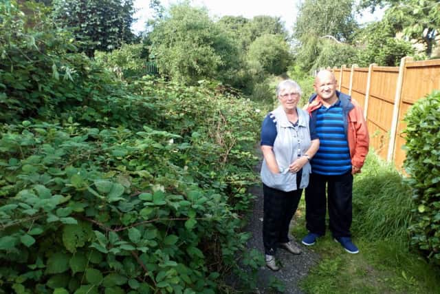 Philip Freestone and Brenda Griffiths alongside the overgrown footpath at the rear of Thomas Gibson Way