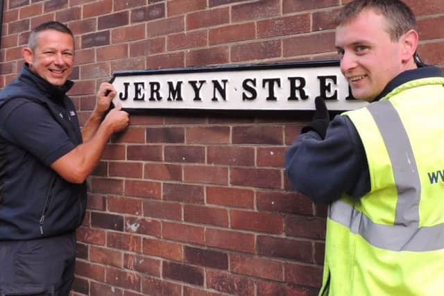 Window cleaners Paul Dunham and Matt Gillard putting back one of the refurbished cast iron street names in Sleaford. EMN-180928-092808001