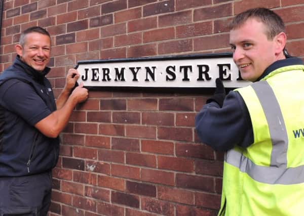 Window cleaners Paul Dunham and Matt Gillard putting back one of the refurbished cast iron street names in Sleaford. EMN-180928-092808001