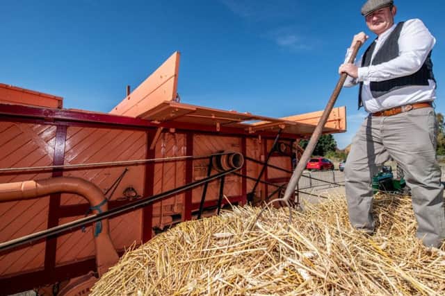 Paul White loading the thresher. EMN-180110-124048001