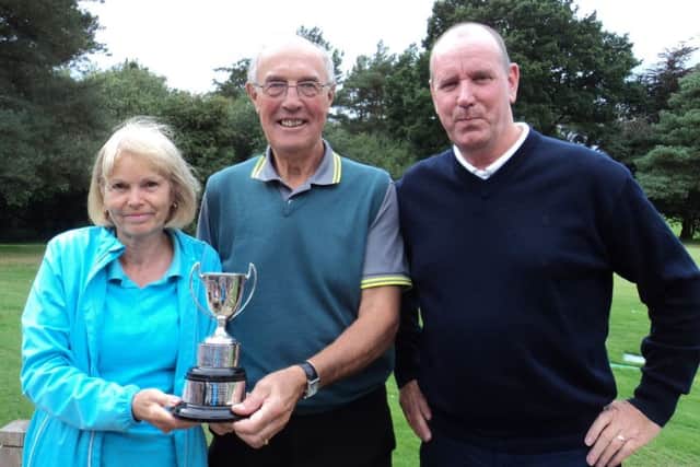 Men's captain Ian Ribey (centre) presents the Ainsworth Trophy to Hilary and Dave Tuhey EMN-180810-171220002