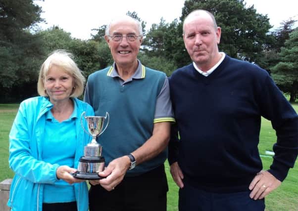 Men's captain Ian Ribey (centre) presents the Ainsworth Trophy to Hilary and Dave Tuhey EMN-180810-171220002