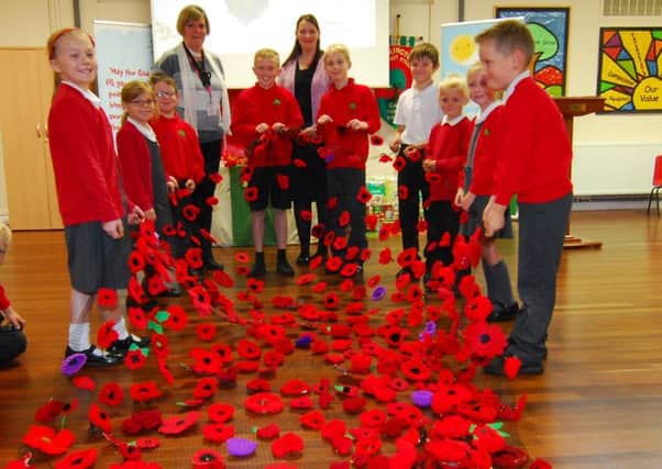 Ruskington priest-in-training Sara Davies and Chestnut Street School head Claire Buckley with pupils from the collective worship council and some of the hundreds of handmade poppies attached to be hung in church in the run up to Remembrance Sunday. EMN-181015-175135001