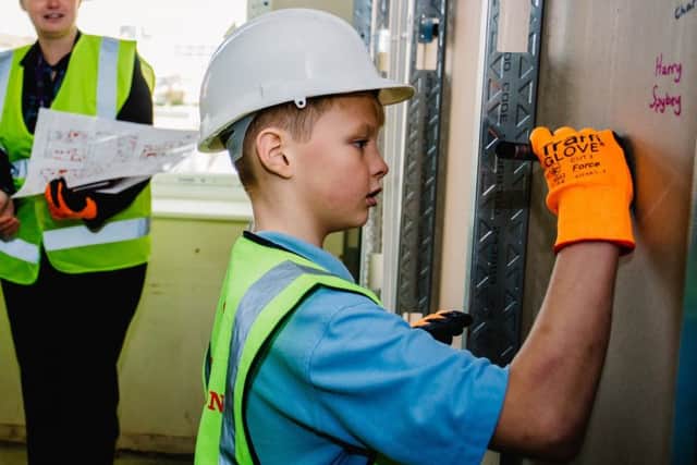 One of the pupils signs his name on the plasterboard. Picture: Jakt Photography. EMN-181228-102647001