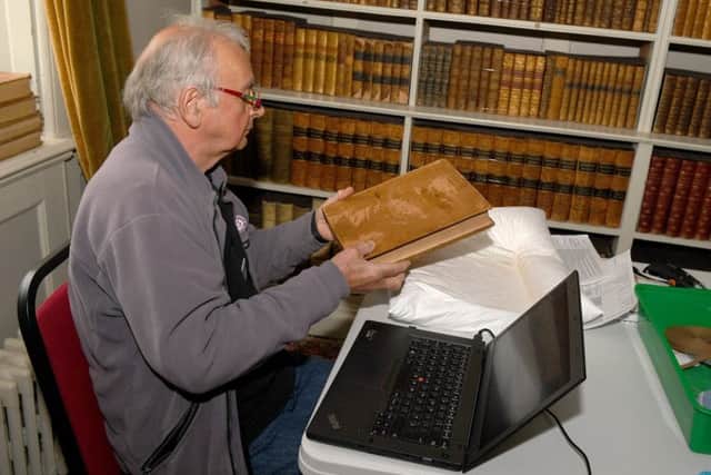 Volunteer Nick O'Farrell doing a condition survey on the biiks in the library. EMN-190705-092534001