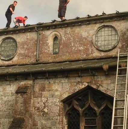 Local builders help to lay a temporary cover the roof of St Swithun's in Bicker before the rain gets in.