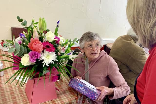 Barbara with the bouquet and chocolates donated by the community.